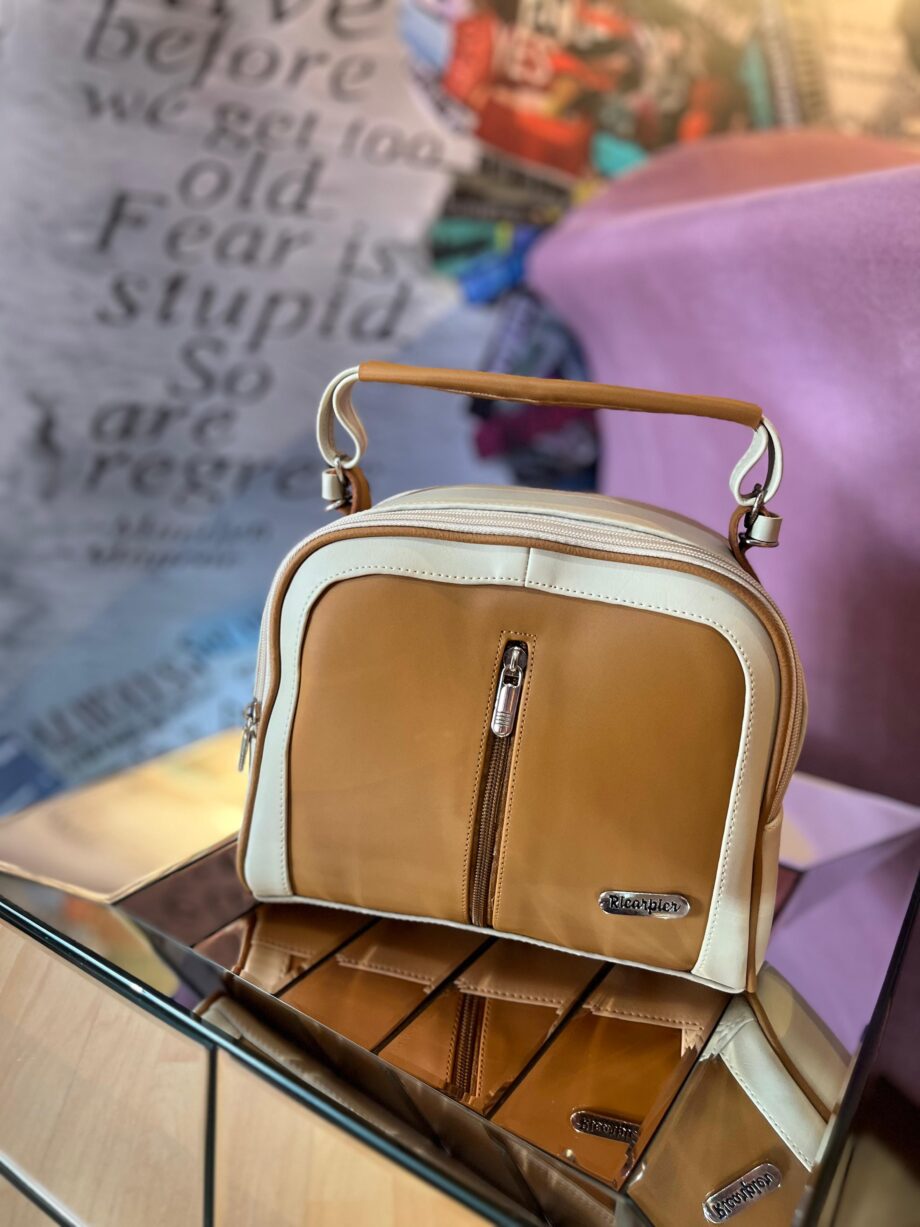 Bolso bicolor de mujer marrón y blanco con asas superiores y correa ajustable para el hombro.